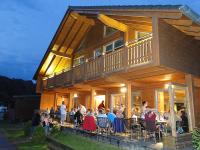 a group of people sitting outside of a house at Camping Bissen in Esch-sur-Sûre