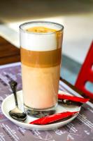 a glass of coffee on a plate with a spoon at Old Town Boutique Hotel in Bucharest