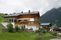 a large house on a hill with mountains in the background at Spatla Appartements in Gaschurn