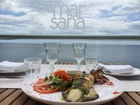 un plato de comida en una mesa con el océano en el fondo en Hotel Boutique Milla de Plata, en Torreguadiaro