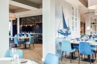 ein Restaurant mit blauen Stühlen und Tischen und einem Segel an der Wand in der Unterkunft Küstenperle Strandhotel & Spa in Büsum