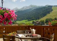 a table and chairs on a balcony with a view of mountains at Carlina in La Clusaz