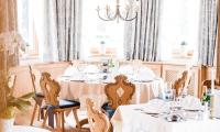 a dining room with white tables and chairs and a chandelier at Forster's Naturresort in Neustift im Stubaital