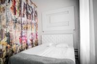 a bedroom with a white bed with a colorful wall at Homelike Hotel in Daugavpils
