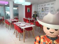a restaurant with tables and a person standing in the background at Hotel del Juguete in Ibi