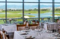 Un comedor con mesas y sillas con vista a un campo de golf. en Theodora Golf Club, en Alba Iulia