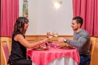 a man and woman sitting at a table with a glass of wine at Hotel Villa Rosella Park & Wellness in Canazei