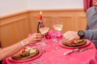 two people holding glasses of white wine at a table at Hotel Villa Rosella Park & Wellness in Canazei