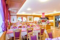a restaurant with tables and chairs in a room at Hotel Villa Rosella Park & Wellness in Canazei