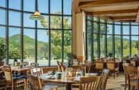a restaurant with tables and chairs and large windows at High Peaks Resort in Lake Placid