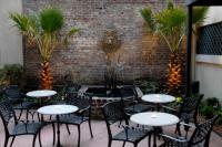a patio with tables and chairs in front of a brick wall at Foley House Inn in Savannah