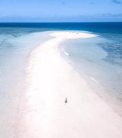 a person standing on a white beach in the ocean at Hotel Maharajah in Mamoudzou
