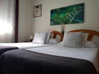 Un dormitorio con dos camas y un cuadro en la pared. en Pensión Leyre, en Pamplona