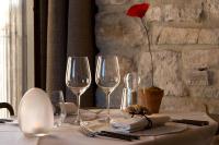 einen Tisch mit Weingläsern und eine Blume in einer Vase in der Unterkunft La Maison du Passage - Chambres - Suites premium, Spa, Piscine et Restaurant in Martignargues