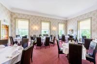a dining room with tables and chairs and windows at Owston Hall Hotel in Doncaster