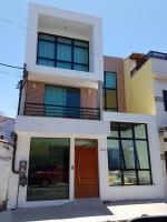 a white building with a red door and windows at Pousada la Portella in Cabo Frio