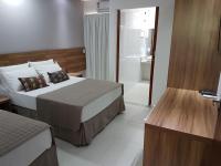 a hotel room with two beds and a bathroom at Pousada la Portella in Cabo Frio