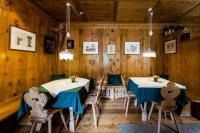 - deux tables et des chaises dans une chambre dotée de murs en bois dans l'établissement B&B Pizzeria Zur Traube, à Montagna