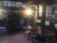 een bar met 2 tafels en stoelen en een open haard bij Crown Inn in Rhayader