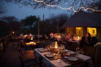 un gruppo di persone seduti ai tavoli al ristorante di notte di Taranga Safari Lodge a Rundu