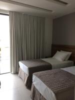 a hotel room with two beds and a window at Pousada la Portella in Cabo Frio