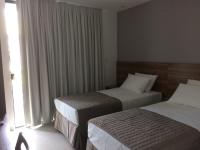a hotel room with two beds and a window at Pousada la Portella in Cabo Frio