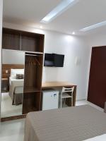 a bedroom with a bed and a desk and a television at Pousada la Portella in Cabo Frio
