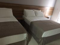two beds in a hotel room next to each other at Pousada la Portella in Cabo Frio