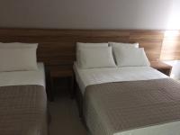 a hotel room with two beds with white pillows at Pousada la Portella in Cabo Frio