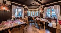 ein Restaurant mit langen Tischen, Stühlen und Fenstern in der Unterkunft Landhaus Lenzenhof in Reit im Winkl