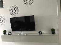 a flat screen tv on a white wall with potted plants at Manyi Apartman in Debrecen