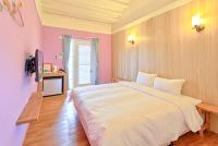 a bedroom with a large white bed with pink walls at Love Summer Hostel in Hengchun South Gate