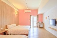 a hotel room with two beds and a tv at Love Summer Hostel in Hengchun South Gate