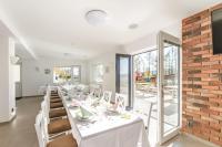 a dining room with white tables and chairs and a brick wall at Penzion DaJa in Horní Planá