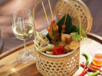 a basket of food next to a glass of wine at Sarikantang Resort & Spa, Koh Phangan in Haad Rin