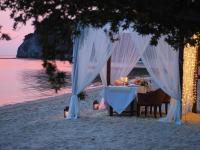 a dinner table on the beach with white curtains and lights at Sarikantang Resort & Spa, Koh Phangan in Haad Rin