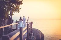 a bride and groom standing on a dock overlooking the ocean at Sarikantang Resort & Spa, Koh Phangan in Haad Rin