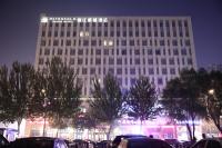 Un edificio alto con coches aparcados delante. en Metropolo Shenyang Wanda Plaza-Beiyi Road, en Shenyang