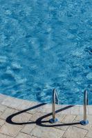 a swimming pool with blue water and two metal rails at Entourage sur-le-Lac in Lac-Beauport