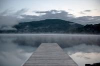 a dock on a lake with a mountain in the background at Entourage sur-le-Lac in Lac-Beauport
