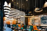 Un restaurante con mesas, sillas y lámparas de araña. en Pullman Berlin Schweizerhof, en Berlín