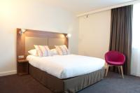 a hotel room with a large bed and a pink chair at Campanile Limoges Centre - Gare in Limoges