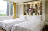 two beds in a bedroom with a clock on the wall at Kiwi Express Hotel - Zhong Zheng Branch in Taichung