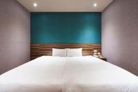 a large white bed in a room with a green wall at Tomorrow Hotel in Taipei