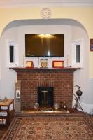 a living room with a fireplace with a flat screen tv at Gatwick Castle B&B in Horley