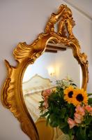 an ornate gold mirror with flowers in front of a bed at Hotel Orion in Venice