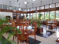 Un restaurante con mesas y sillas de madera y plantas. en The Sanctuary Hotel Resort Spa, en Port Moresby