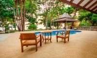 a table and chairs and an umbrella next to a pool at Koh Jum Beach Villas "A member of Secret Retreats" in Ko Jum