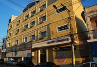 Un edificio amarillo en una calle con coches aparcados delante. en Hotel Oriente, en Itajubá