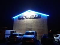 a hotel restaurant with cars parked in a parking lot at night at La Godinière in Cholet